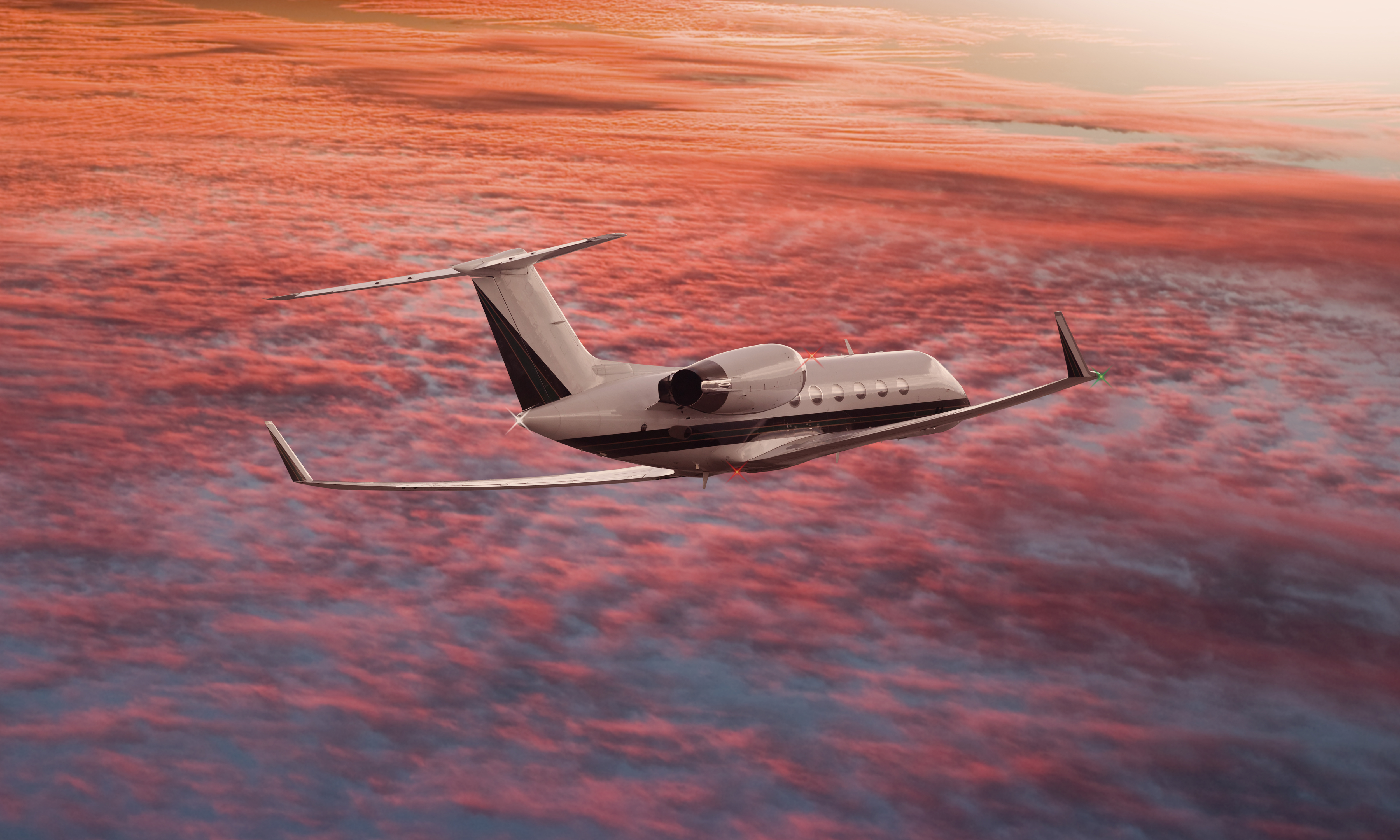 Private jet flying above sunset clouds